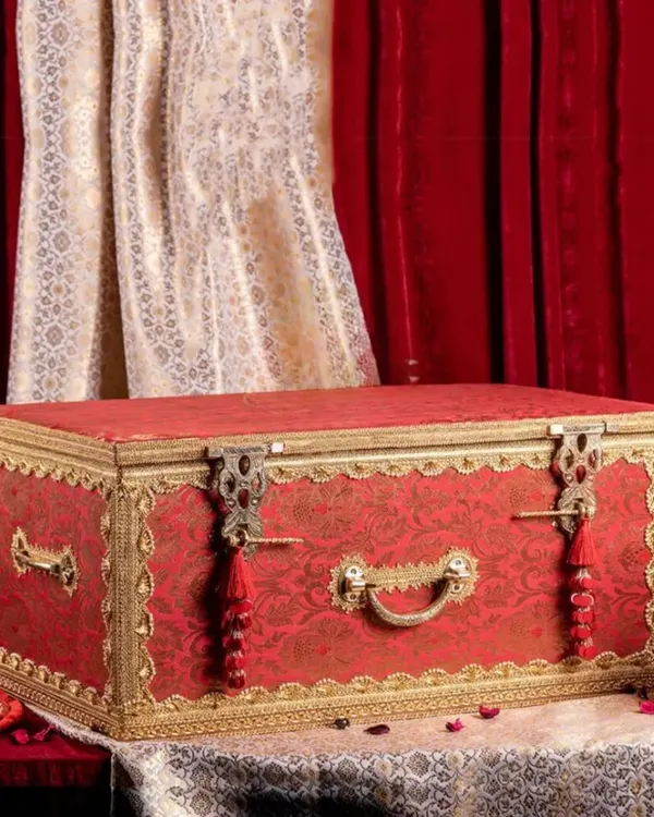 This traditional red and gold brocade sanduk is a centerpiece for any trousseau. I source and design these ornate trunks to give your wedding gifts a truly royal presentation, ensuring they are treasured for years to come.