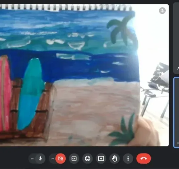 A student proudly shows his finished beach scene painting during our online class. I provide step-by-step guidance to help them create beautiful art from home.