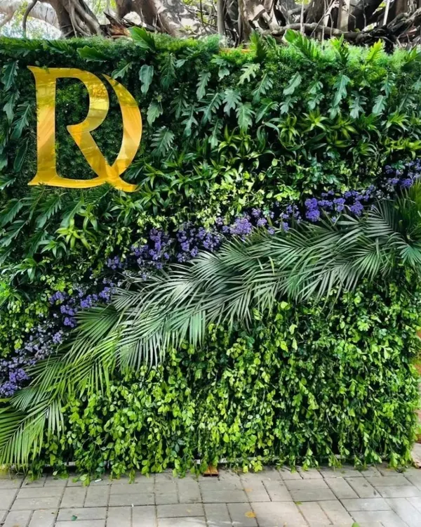 This photo booth backdrop is a dense wall of natural greenery, featuring a diagonal arrangement of purple flowers and palm leaves. I added a custom gold monogram to personalize it for the event.