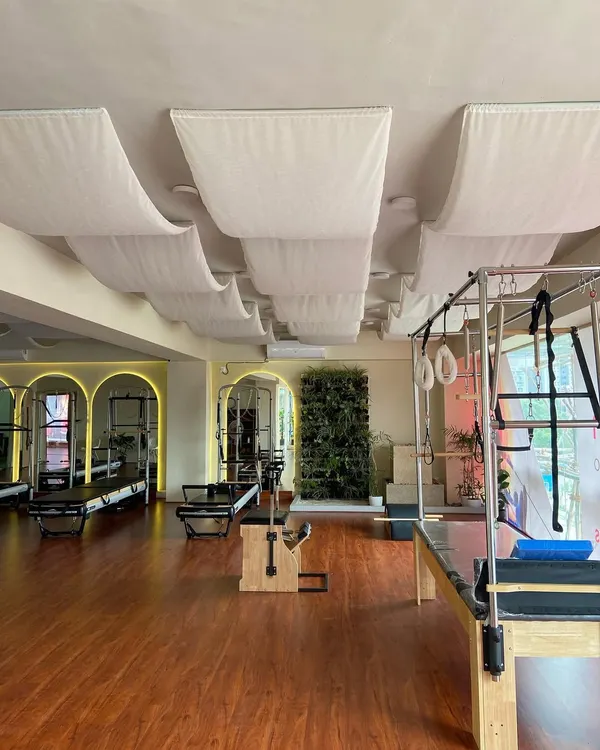 A wide view of the studio, showcasing the spacious layout with multiple reformers, a Cadillac, and a Wunda chair. The design promotes a feeling of openness and calm.