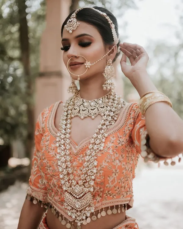 A detailed close-up of a stunning multi-layered pearl and polki rani haar, paired with a matching nath and maang tikka. This is the ultimate accessory for a regal bridal shoot.