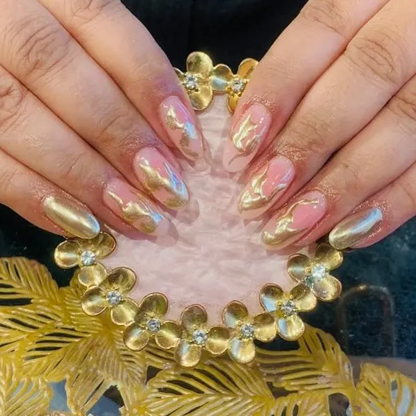 A stunning liquid gold effect. This set features a mix of full chrome gold nails and nails with a gold chrome swirl over a pink base.