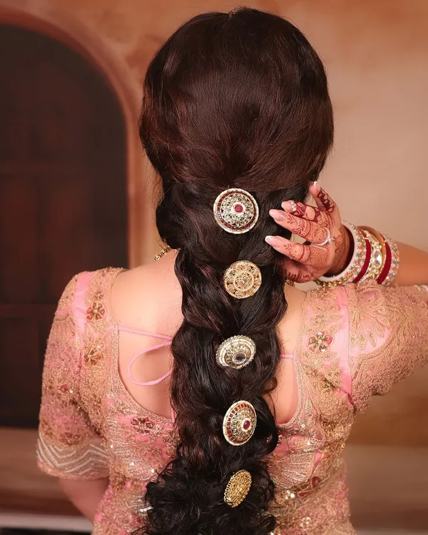 A detailed shot of a stunning bridal braid. This thick, textured braid is adorned with traditional gold accessories, creating a look that is both modern and timeless.