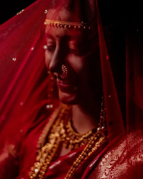 We believe a bridal portrait should be more than just a picture. It should be a feeling. Here, we used a traditional red veil and dramatic, low-key lighting to create a moment of quiet contemplation, transforming a simple portrait into a piece of timeless art.
