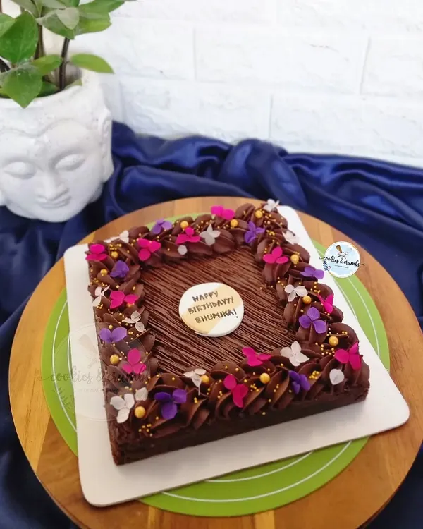 A rich, 8-inch Hazelnut Brownie Cake. I decorated the edges with chocolate frosting and a sprinkle of edible butterflies and flowers for a pop of color.