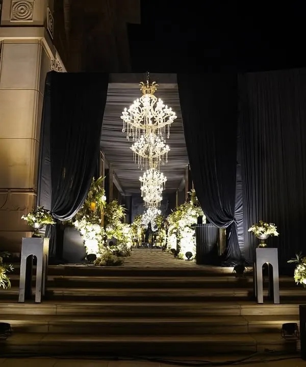 The entrance to our 'Black Luxe' Sangeet. Grand chandeliers, dramatic black drapes, and soft white blooms created a luxurious and moody setup for a night to remember.
