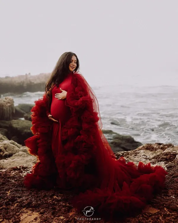 This dramatic, deep red ruffled gown is a true showstopper, perfect for creating breathtaking photos against a natural backdrop like the sea. The layers of tulle add texture and movement, ensuring your maternity photos are nothing short of epic.