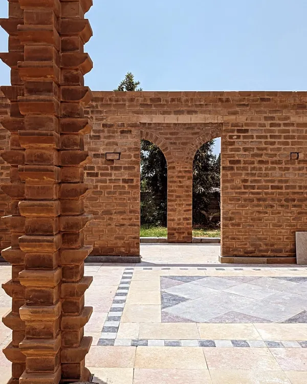 A view through brick archways into a beautifully tiled courtyard. This project showcases my work in creating durable and artistic hardscape structures that frame the garden and define outdoor rooms.