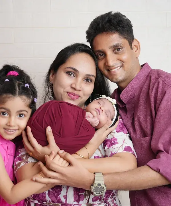 And then there were four! This beautiful family portrait captures the joy of a growing family. The older sister is so excited to meet her new sibling, a precious memory for everyone.