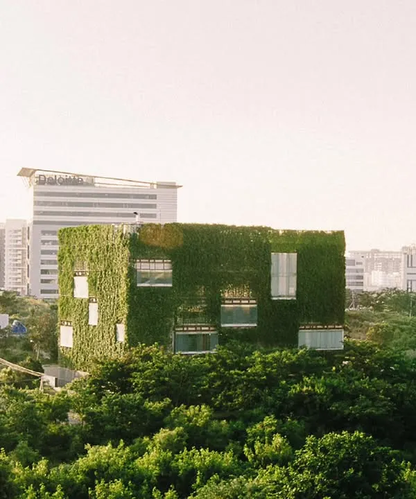 The KMC Headquarters stands as a verdant cube amidst the concrete and glass of Hyderabad. This living facade is not just an aesthetic choice but a high-performance building skin that actively cools the interior and connects the workspace to the natural world.