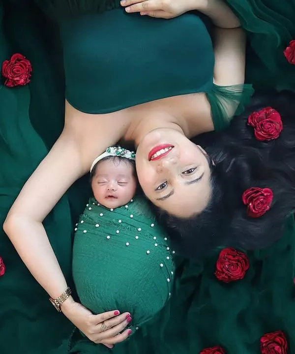 This is one of my absolute favorite poses for a mother and newborn. The rich green fabric and scattered red roses create a stunning, artistic portrait that feels like a painting. It’s a beautiful celebration of motherhood.