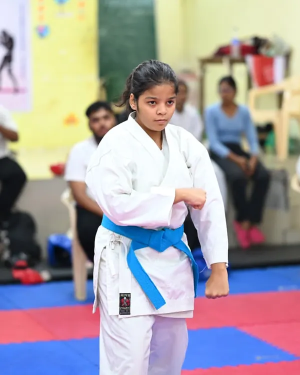 A young student demonstrates a strong, focused stance during her karate training. Her blue belt signifies her progress and dedication to the art.