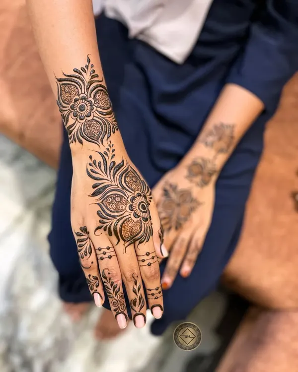 A classic and elegant Arabic henna design. This style features bold floral and vine patterns that flow diagonally across the hand, leaving some skin exposed for a beautiful contrast.