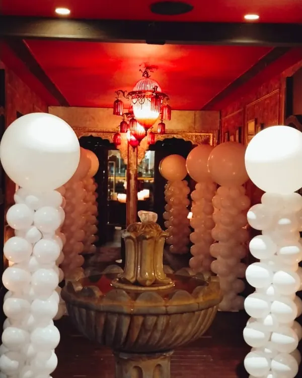 An elegant and dramatic entrance created with tall white balloon pillars. This white-themed decoration transforms a hotel corridor into a sophisticated event space, perfect for weddings or upscale parties.