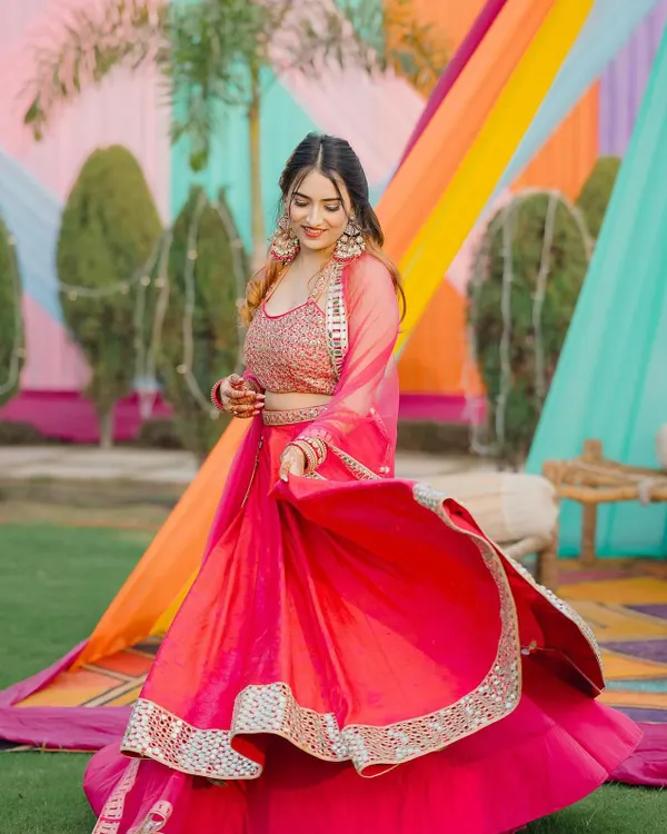 Twirling in a vibrant pink lehenga against a colorful Mehendi backdrop. This shot is all about capturing the festive energy of a wedding.