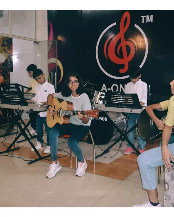 A group of students learning guitar and keyboard together. This setup mimics a real band, teaching them how to play in sync and listen to each other.