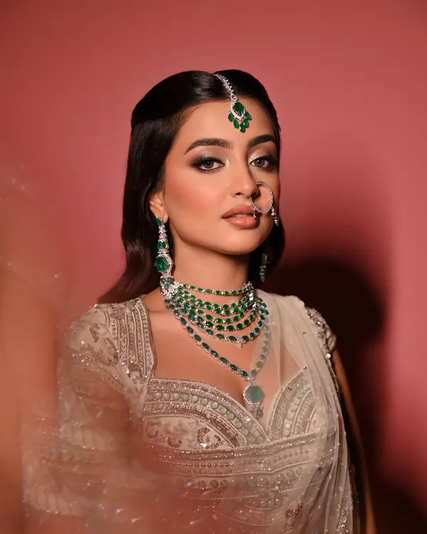 A close-up of the "Moonlit Majesty" look. The focus here is on the silver-toned smokey eye, sharp winged liner, and a soft nude lip, all framed by stunning emerald jewellery.