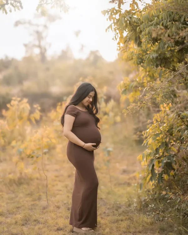 A peaceful solo portrait in a beautiful brown dress, surrounded by the soft, warm light of the setting sun in a natural field setting.