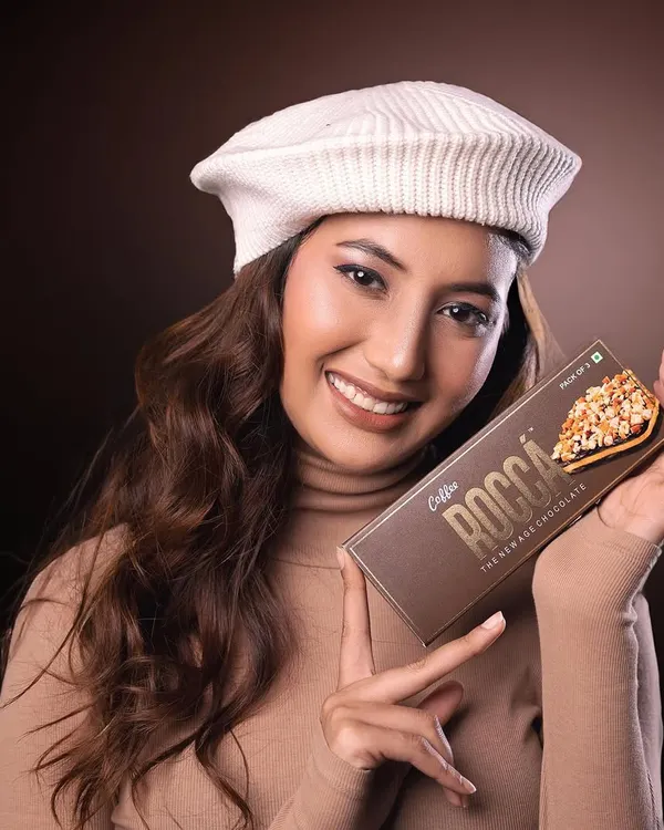 A vibrant commercial portrait for Rocca Chocolates. The model's cheerful expression and direct engagement with the product create an appealing and effective advertisement.