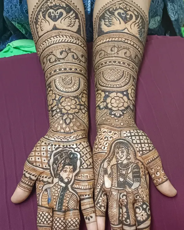 A perfect example of story mehendi, with portraits of the bride and groom on each palm. The design is completed with swan motifs and floral patterns, creating a beautiful narrative of their union.