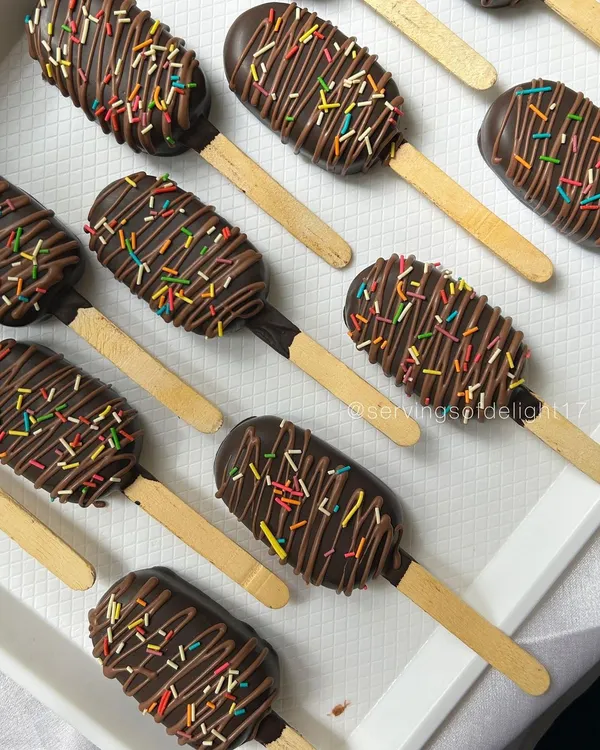 A tray of my classic chocolate cakesicles, drizzled with more chocolate and topped with rainbow sprinkles. They are the perfect party-sized treat.