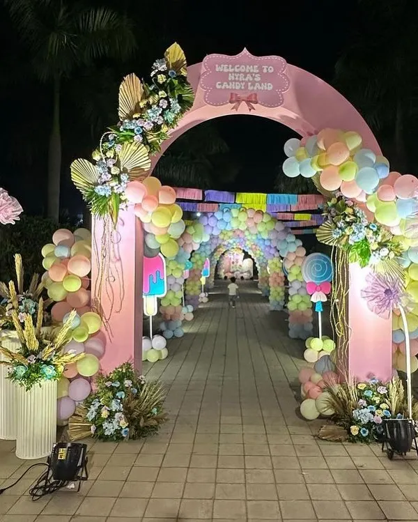 This grand entrance for "Myra's Candy Land" creates an immersive experience for guests from the moment they arrive. The pastel balloon tunnel and themed props set the stage for a magical first birthday party.
