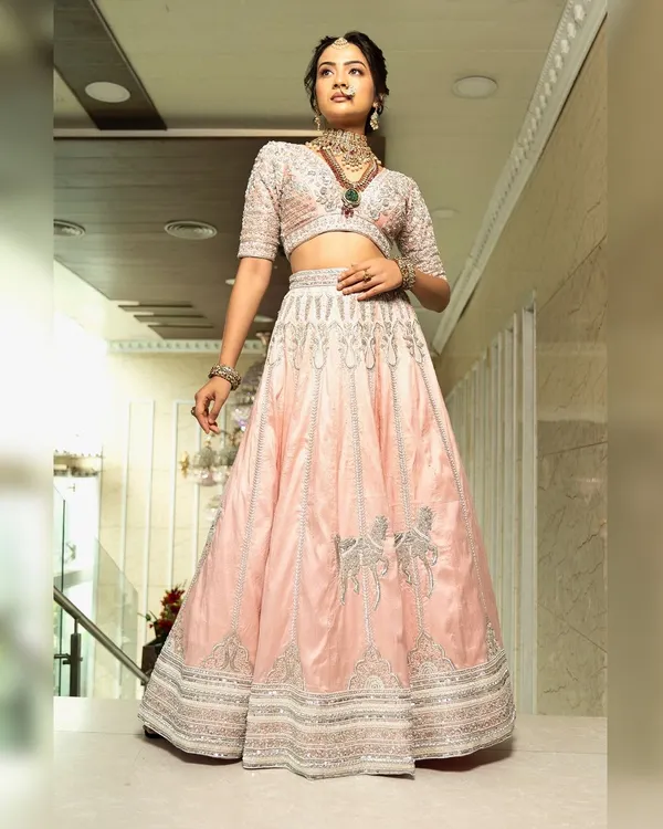 Twirl into a fairytale with this baby pink bridal lehenga. I designed it with intricate horse embroidery on the raw silk skirt and paired it with a heavily handworked blouse and a delicate net dupatta for a truly heavenly look.