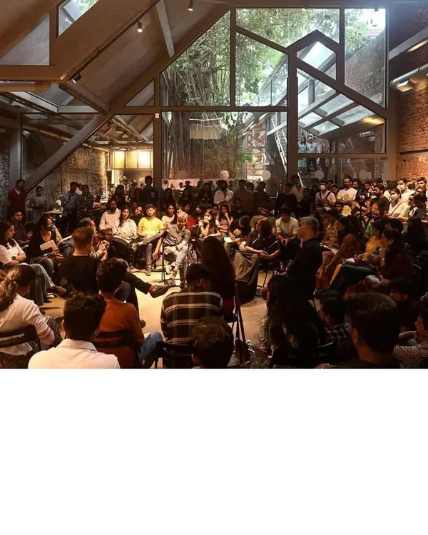 The completed 'Cathedral' space at IF.BE, filled for a public talk. The new roof structure, with its geometric windows, dialogues with the old brick walls and the central banyan tree, creating a dynamic venue for cultural exchange and architectural discourse.