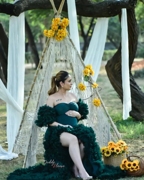 A beautiful boho-themed outdoor maternity shoot. The mom-to-be is seated in a macrame teepee adorned with yellow flowers, wearing a stunning dark green ruffled gown from my collection.