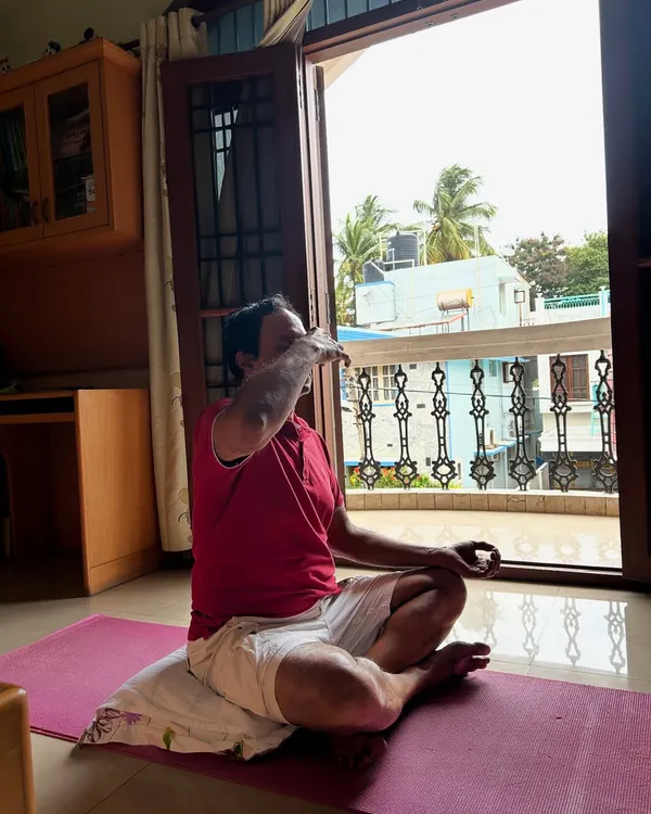 A client practices Nadi Shodhana pranayama (alternate nostril breathing) during an at-home personal training session, focusing on stress reduction and mental clarity.