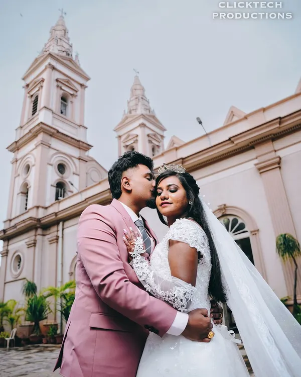A classic wedding portrait of the groom kissing his bride on the forehead, with the church spires rising majestically in the background.