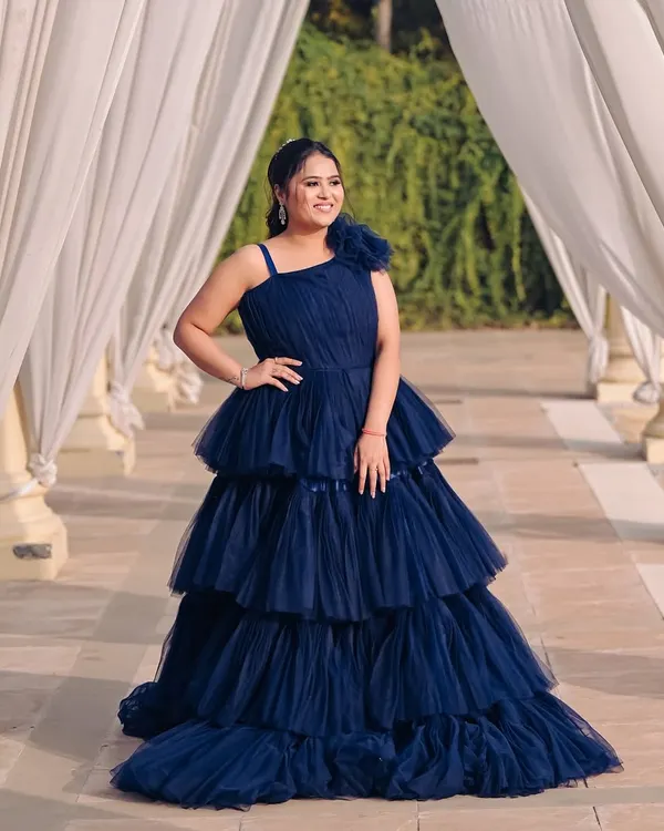 A beautiful shot of a client ready for her pre-wedding shoot in a stunning navy blue tiered gown. The makeup is soft and glamorous, designed to look flawless in the golden hour light.