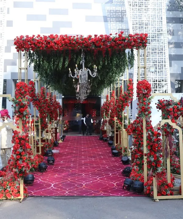 This grand entrance is the epitome of royal splendor. I designed a long walkway covered by a canopy of red roses and greenery, with crystal chandeliers hanging above a plush red carpet, creating an unforgettable welcome for a NESCO wedding.