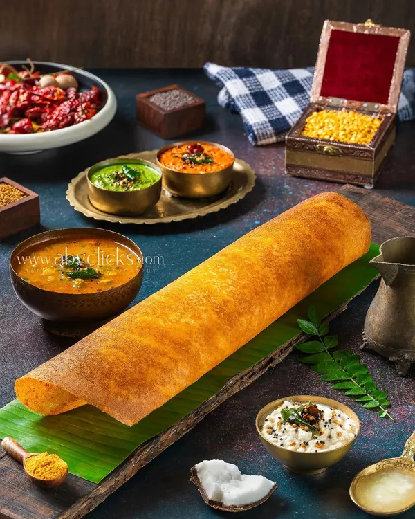 A classic Masala Dosa, styled with a variety of fresh ingredients and spices to create a rich, detailed foodscape. This shot emphasizes the authenticity and complexity of South Indian cooking.