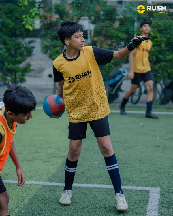A young player in a goalkeeper bib prepares to distribute the ball, showing the versatility we encourage in our players to understand all aspects of the game.