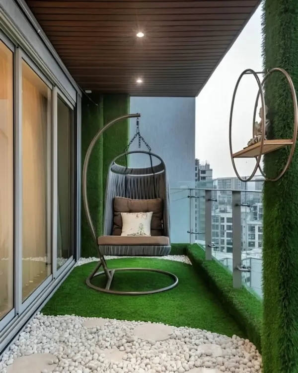 A perfect balcony retreat featuring a comfortable swing chair on an artificial grass floor. The vertical green wall adds privacy and a touch of nature in the middle of the city.