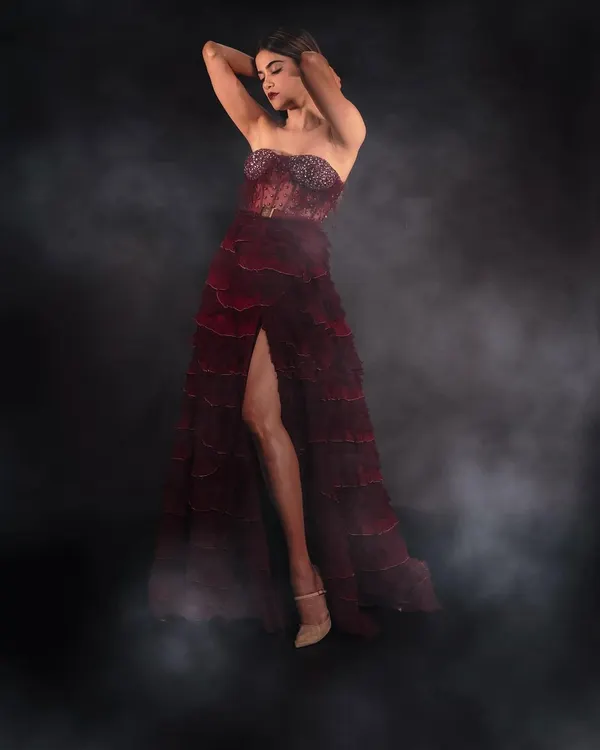 Full-length glamour shot of Aaditi Pohankar. This look is all about drama, with a bold red lip, sculpted cheeks, and a smoky eye, paired with a stunning tiered red gown. Perfect for making a statement on the red carpet.