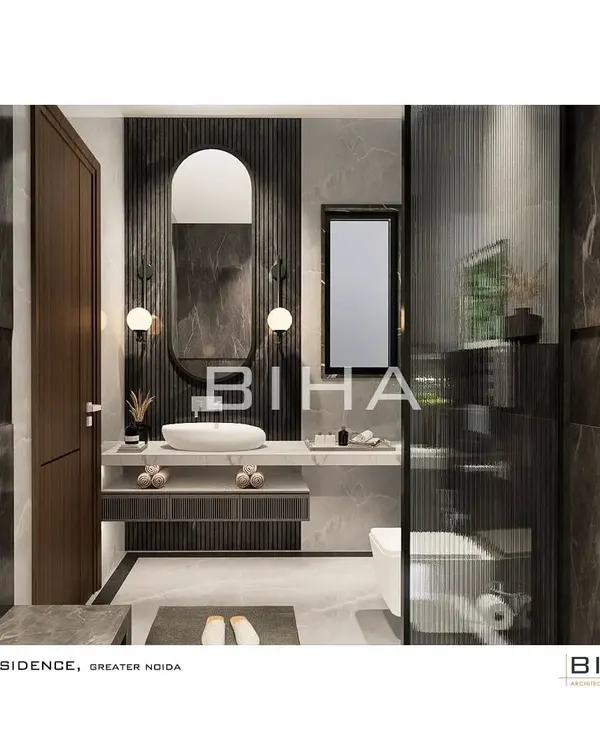 This luxury washroom in Greater Noida features a sophisticated palette of grey marble and dark wood fluting. An arched mirror and contemporary globe sconces soften the clean lines of the floating vanity, which includes open shelving for easy access to essentials.