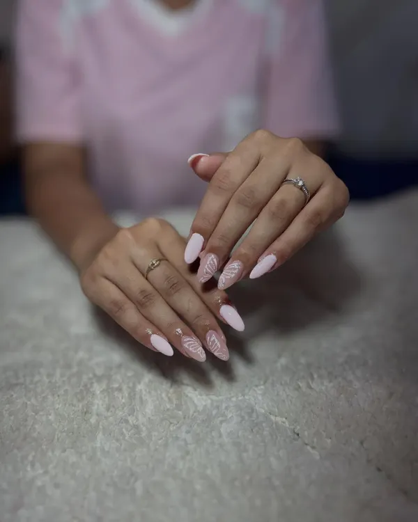 A delicate and elegant design on almond-shaped nails, featuring a soft pink base with intricate white line art.