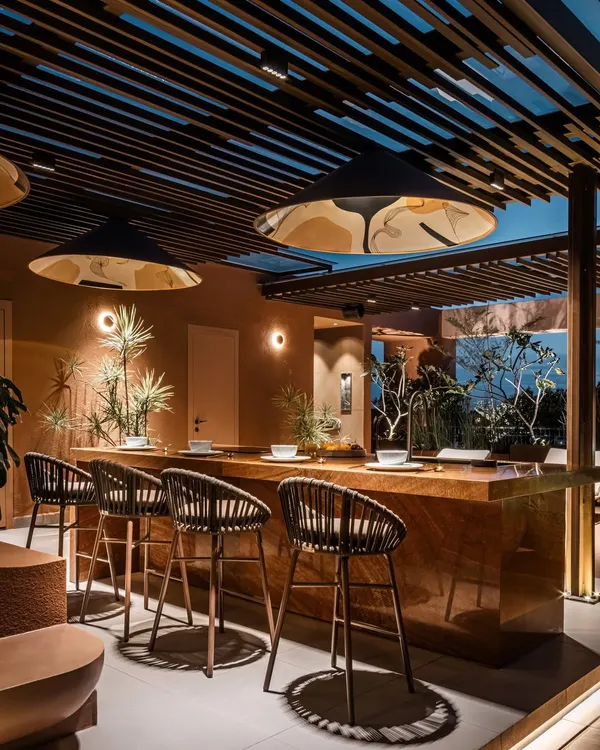 The monolithic bar at the Terra Gardens project, crafted from a single piece of sandalwood traver onyx marble. This outdoor kitchen entertainment zone is designed for hosting, with ample counter space and dramatic lighting.