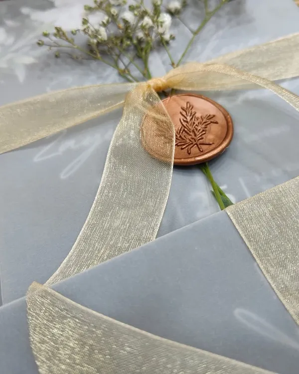 This design captures modern romance with a translucent vellum wrap, secured by a custom wax seal and a delicate sprig of baby's breath. It’s an example of how I combine different textures and materials to create a truly memorable first impression.