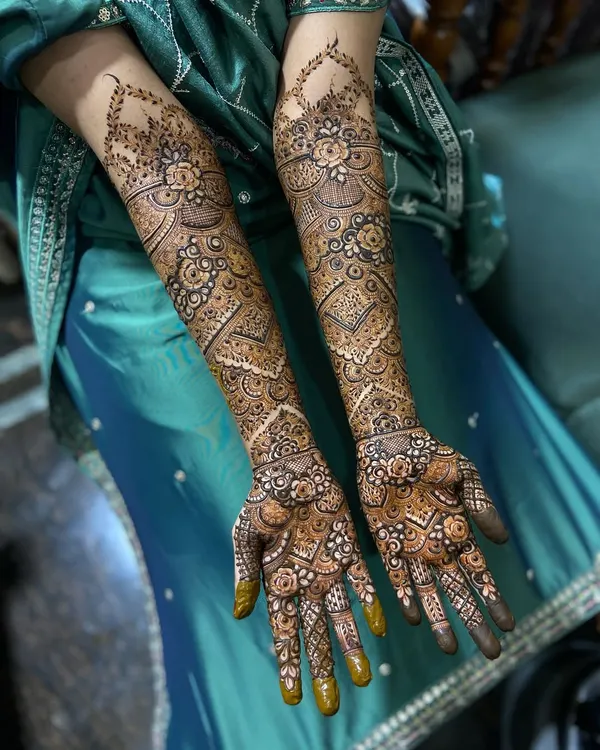 A complete view of a full-coverage engagement henna design. The patterns are symmetrical yet unique on each arm, creating a cohesive and stunning bridal look.