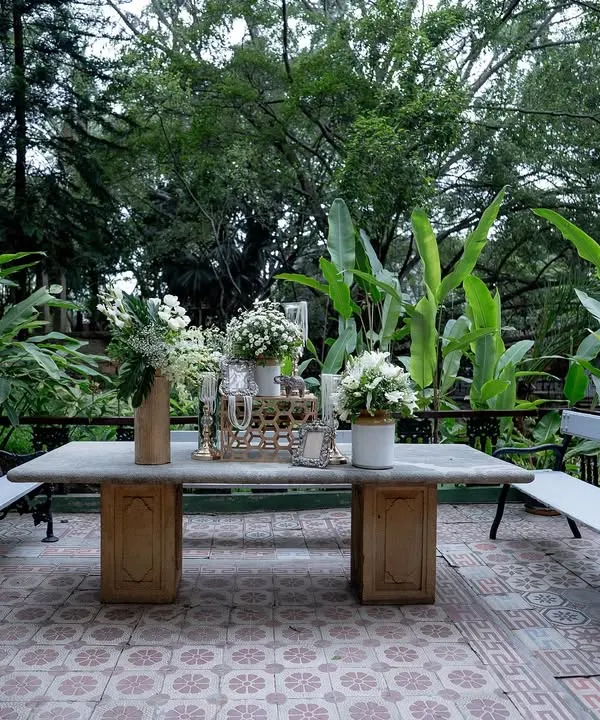 A quiet seating area with a stone table and benches, set amidst the lush greenery of our gardens, perfect for guests to relax.