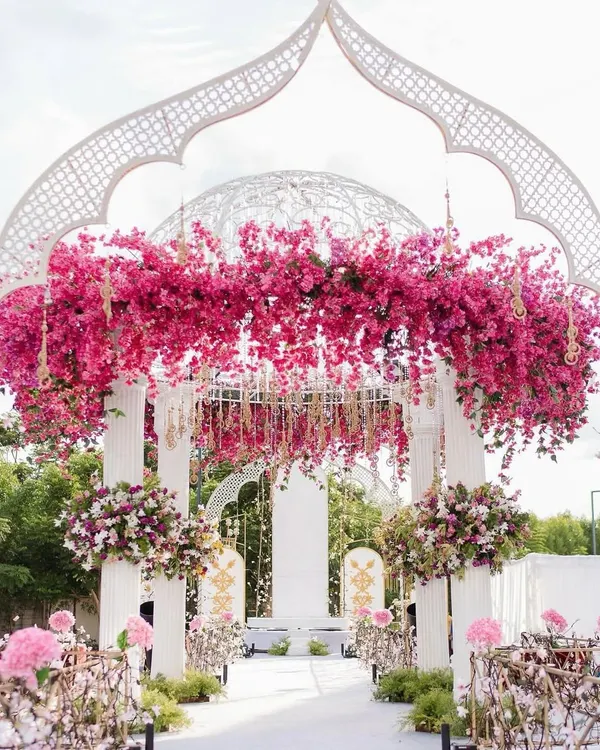 A beautiful floral archway created for a daytime celebration. The white structure is adorned with vibrant pink bougainvillea, creating a stunning entrance and photo opportunity.