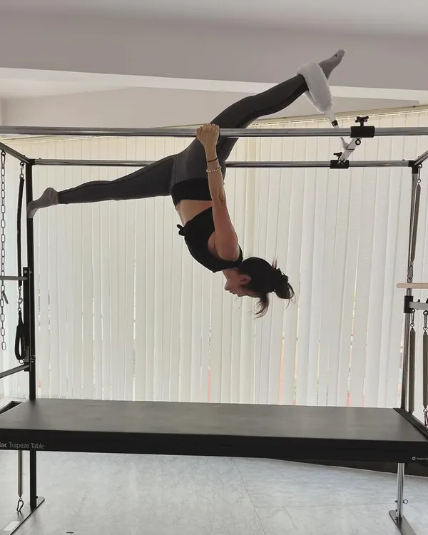 A beautiful split performed while suspended from the Cadillac bars, showcasing both strength and hamstring flexibility.