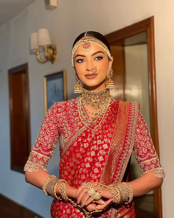 A complete South Indian bridal look featuring a sleek, center parted bun. The hairstyle is designed to perfectly accommodate the traditional matha patti and jhumkas, creating a regal and authentic bridal profile.