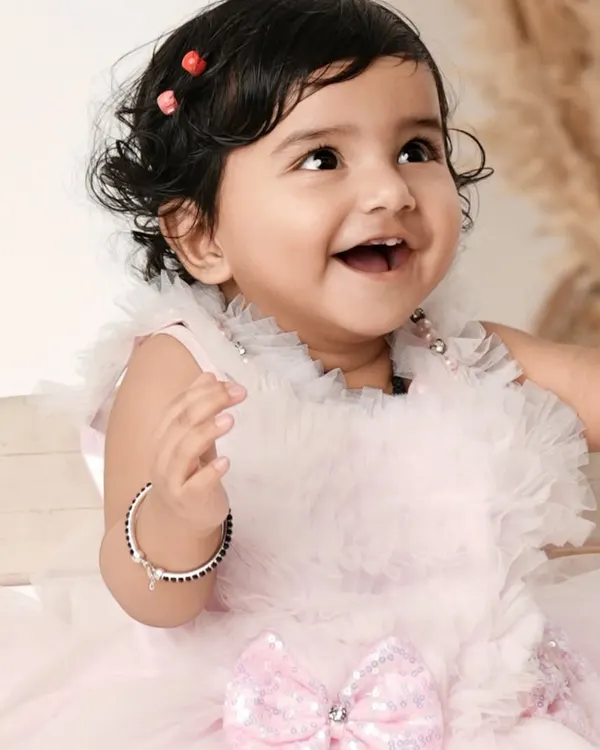 The pure, uncontainable joy of a baby's laugh. This close-up shot of a happy baby girl in a beautiful pink dress perfectly captures her delightful personality.