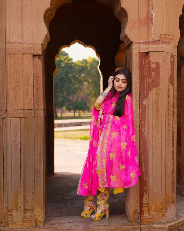 The vibrant pink of this suit creates a stunning contrast with the old stone architecture. I love mixing modern ethnic fashion with timeless backgrounds for a truly unique portrait.
