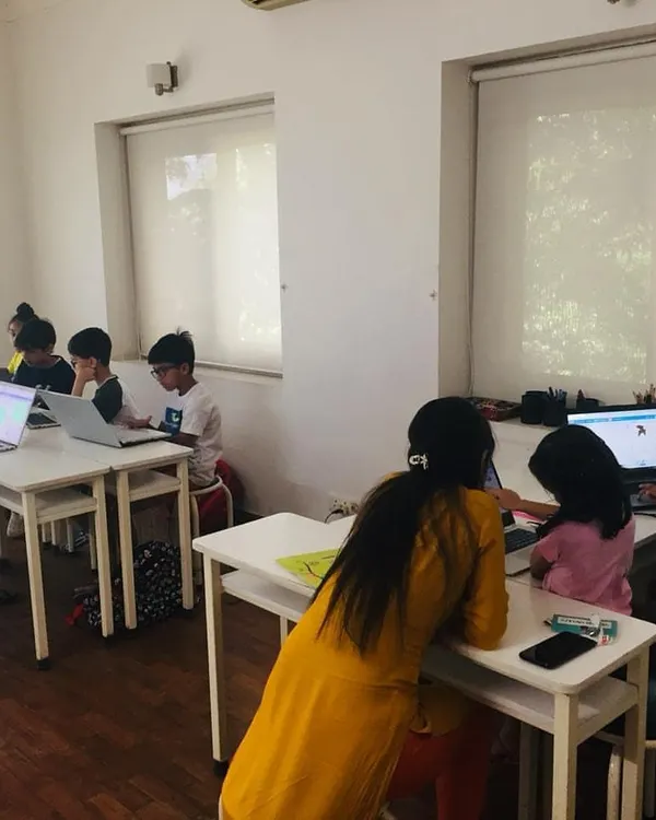 An instructor provides personalized guidance to a young student during an in-person coding class. We maintain a supportive environment to ensure every child understands the concepts at their own pace.