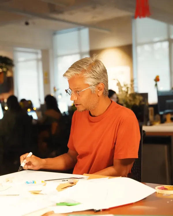 A candid shot of one of our senior architects sketching at a desk. Design is not just what you see; it is the thinking, conversations, and discoveries behind every line, a process that unfolds in our collaborative studio environment.
